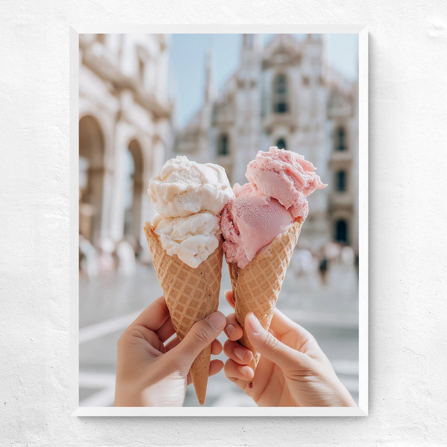 Two ice cream cones held by hands with a blurred architectural background